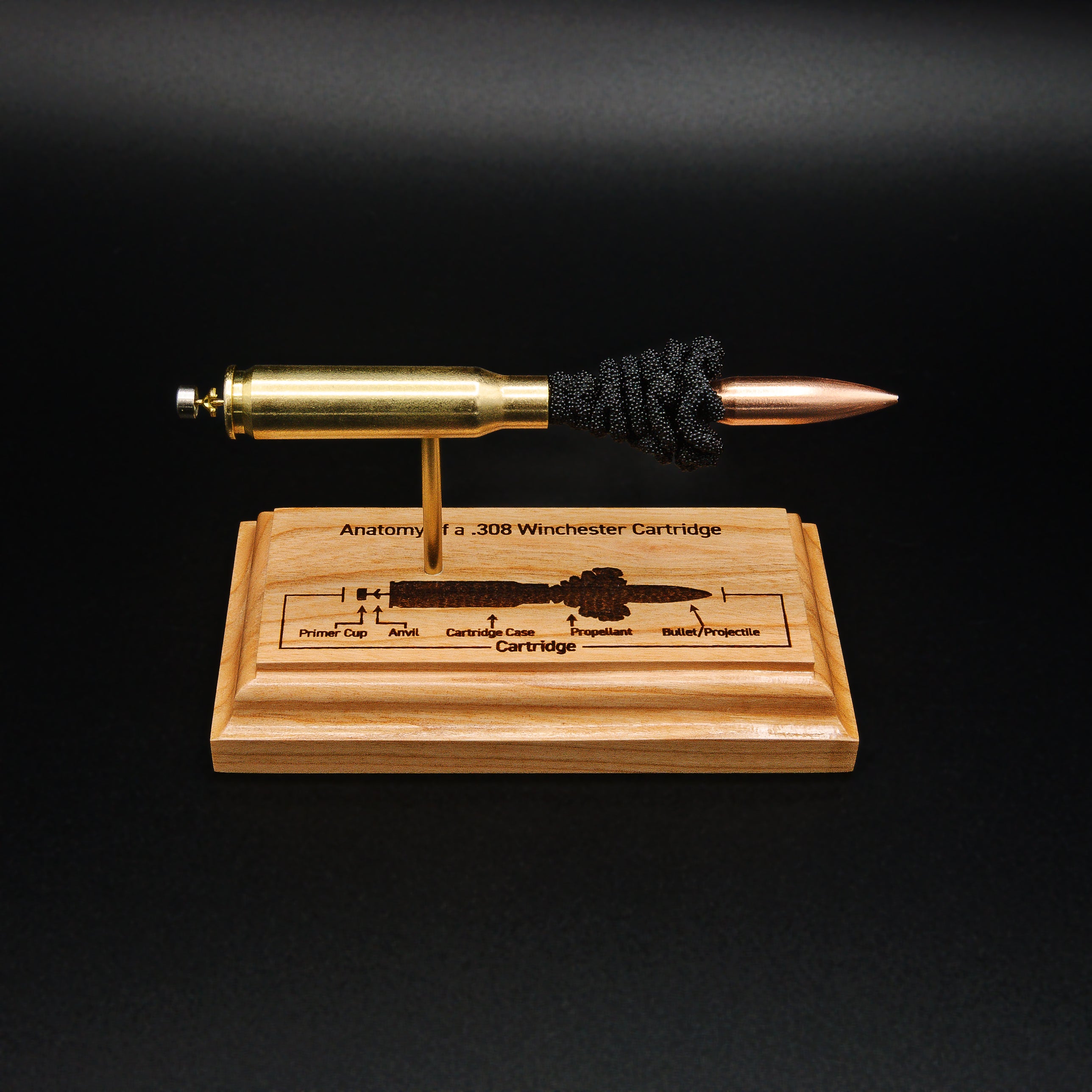 Top front view of a .308 Winchester anatomy display featuring a 168gr Sierra MatchKing HPBT bullet with the engraved cartridge anatomy diagram clearly visible on the cherry wood base.