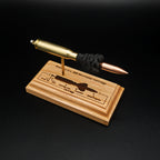 Angled front view of a .308 Winchester cartridge anatomy display featuring a 168gr Sierra MatchKing HPBT bullet, simulated powder, and a laser-engraved anatomy diagram on a handcrafted cherry wood base.