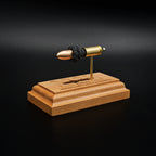 Left back angled view of a handcrafted 9mm Luger cartridge anatomy display featuring a 115gr Sierra FMJ bullet with an engraved anatomy diagram showing the primer cup, anvil, cartridge case, powder, and projectile that is mounted on a solid cherry wood base.