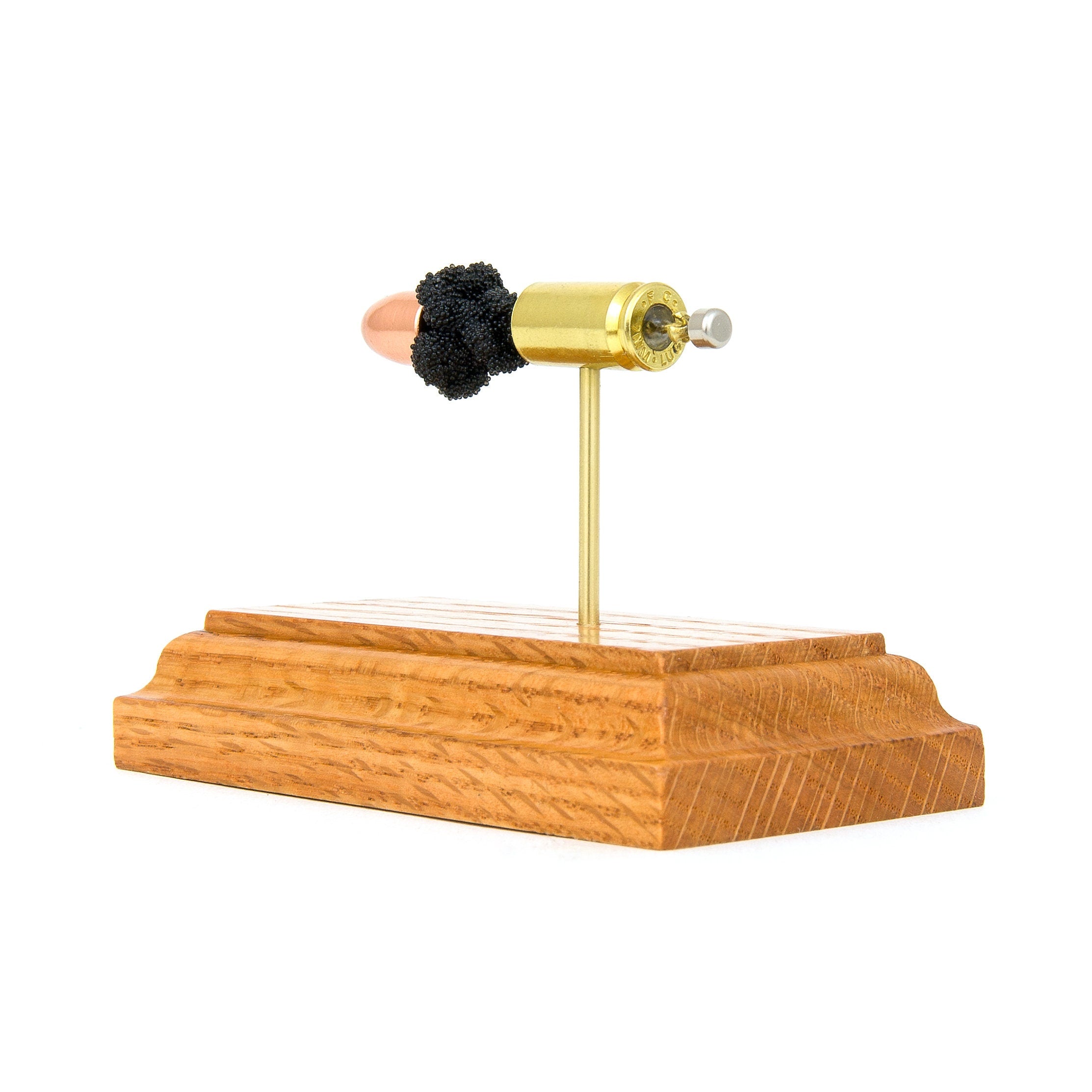 Inert 9mm Luger FMJ cartridge model mounted on hardwood base