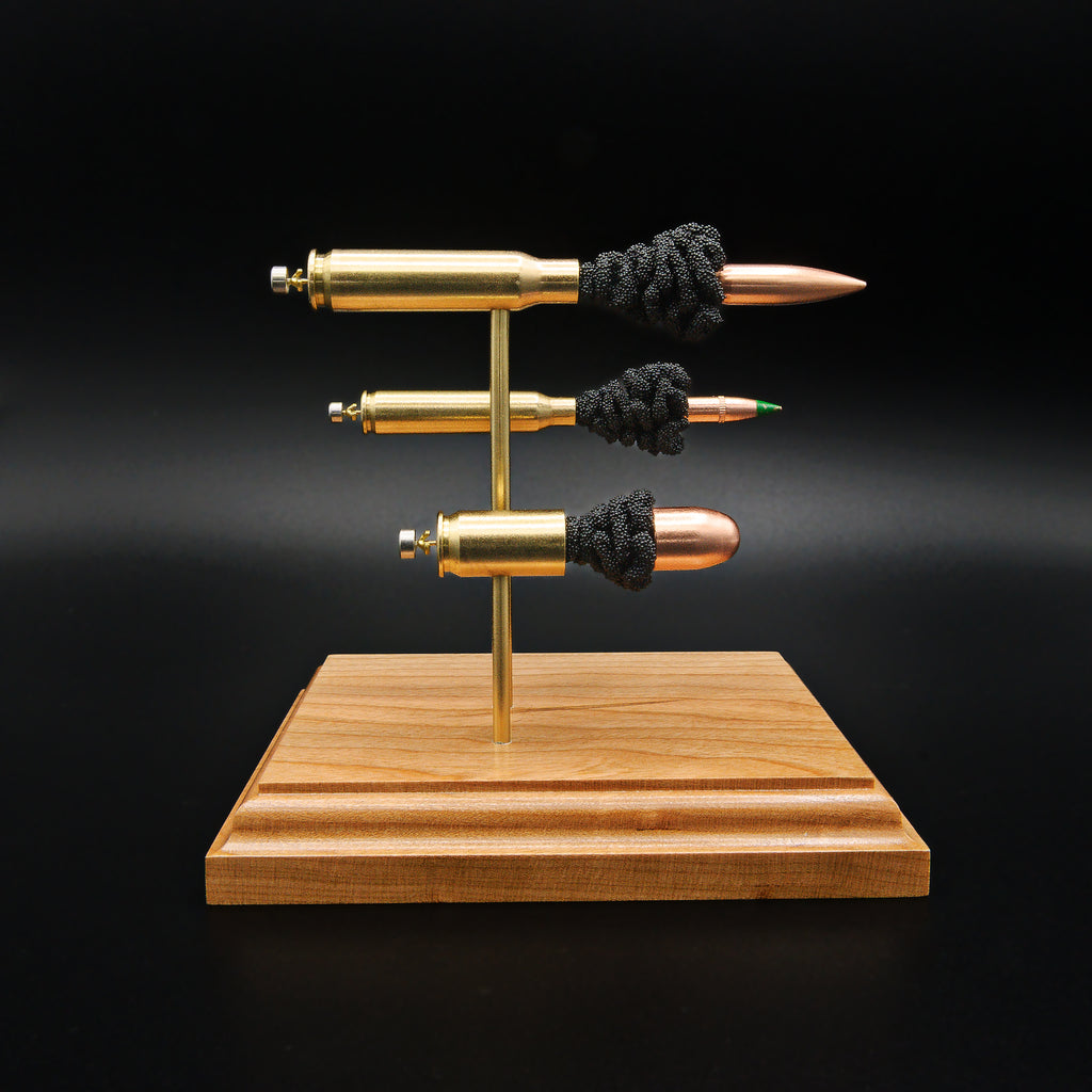 Side view of a handcrafted triple caliber exploded ammunition display featuring a .308 Winchester 168gr Sierra MatchKing HPBT, 5.56×45mm M855 Green Tip, and .45 Auto 220gr Sierra FMJ mounted on a premium cherry wood base.