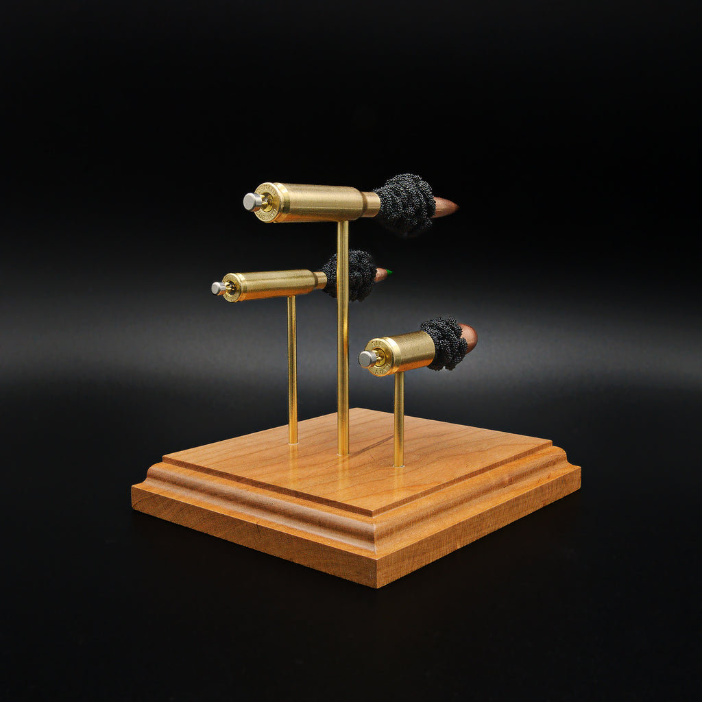 Rear three-quarter view of a handcrafted triple caliber anatomy ammunition display featuring a .308 Winchester 168gr Sierra MatchKing HPBT, 5.56×45mm M855 Green Tip, and .45 Auto 220gr Sierra FMJ mounted on a cherry wood base.